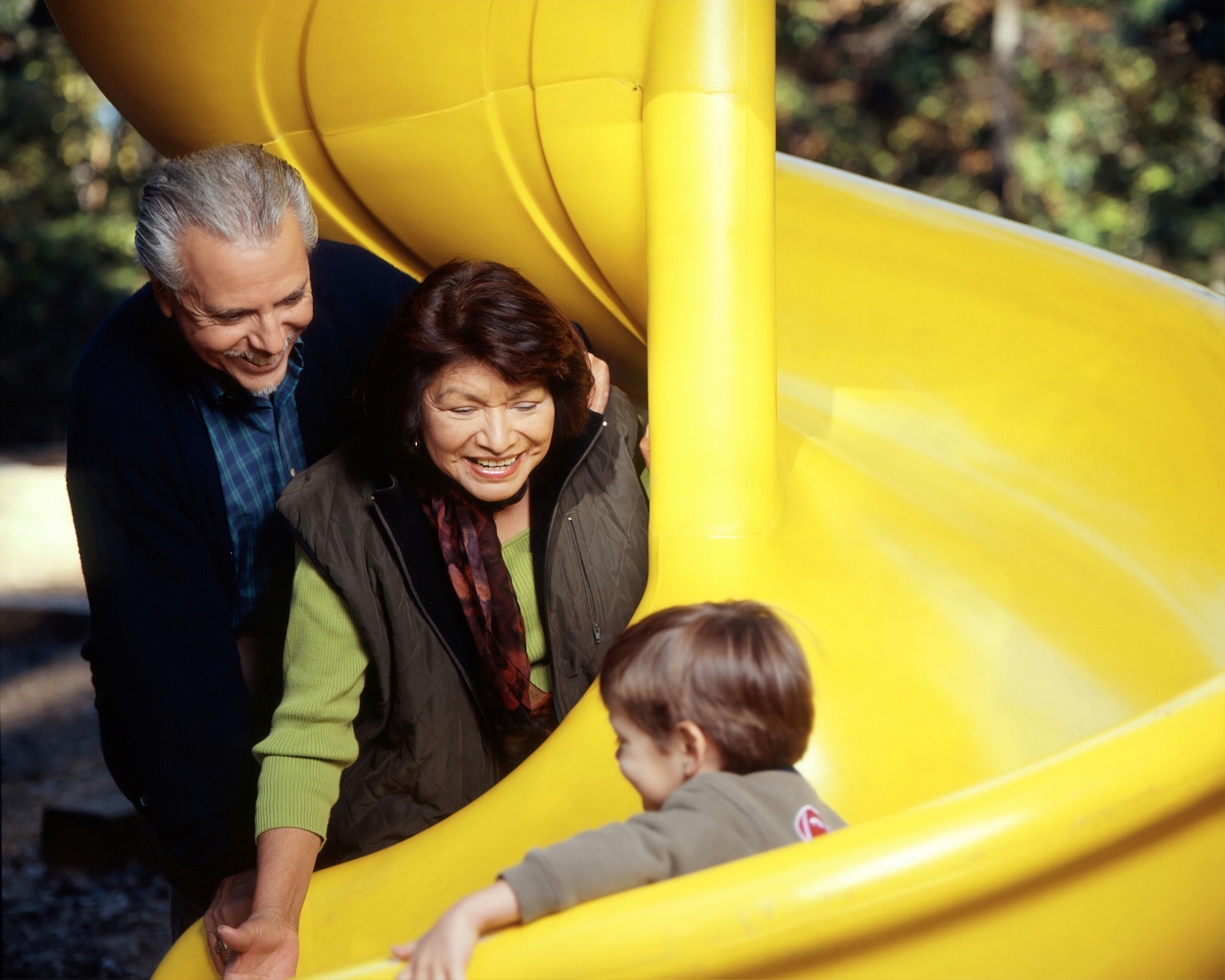 grandparents with grandkid on a yellow slide